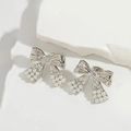 Silver bow-shaped earrings with white pearls and zircon accents on a clean stone background - Silver Bowknot with Small Pearl