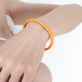 Vibrant orange enamel bangle with gold finish shown on wrist for a minimalist modern look - Orange