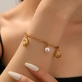 Gold chain bracelet featuring seashell, conch and pearl charms on a woman's wrist - Starfish Conch Beach Bracelet