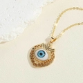 Detailansicht eines goldenen Herzanhängers mit blauem Auge und Sonnenstrahlstruktur - Herzanhänger