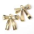 Detail of two gold-toned metal bow pendants with hanging loops for DIY jewelry making - Gold