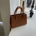 Vintage brown oil wax leather handbag on a windowsill with elegant decor and soft lighting - Brown