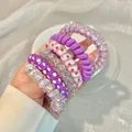 Colorful spiral hair ties in purple and star patterns shown in hand for daily hair styling - 2# Taro Purple Patterns (6pcs Bag)