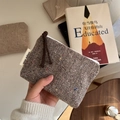 Close-up of brown herringbone wool mini pouch featuring a zipper and a fabric brand label - Brown