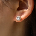 Macro shot of gold halo stud earrings with a large round central zircon on the ear - Gold with White Zircon