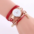 Gros plan d'une montre bracelet en cuir rouge avec boîtier doré au poignet féminin - Rouge