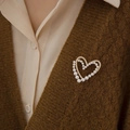 Broche en forme de cœur doré avec perles et zircons sur un gilet en maille marron - Double Cœur Doré (077)