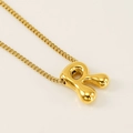 Golden balloon style letter R necklace pendant with glossy finish on beige background - Letter R