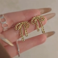 Elegant gold bow earrings with a vintage metallic finish shown in a hand display - Gold Bowknot Shape