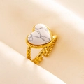 Macro shot of gold stainless steel ring with white heart turquoise on beige silk fabric - Gold-White Stone