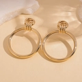 Dettaglio ravvicinato di orecchini a cerchio geometrici dorati su una superficie beige elegante - Oro