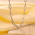 Macro shot of silver paperclip chain necklace on yellow silk and rough stone background - H63 Thick Cross Link Silver Necklace