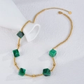 Collier bohème à perles dorées avec cinq cubes géométriques verts sur fond texturé blanc - Or/Vert