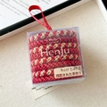 Dettaglio di elastici per capelli intrecciati rosso oro in confezione regalo trasparente - Set Natalizio Rosso