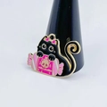 Detail of black cat enamel charm holding pink Halloween candy on a white background - Candy Black Cat