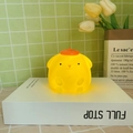 Warm yellow cartoon dog night light shaped like Pompompurin on a white book - Fat Pompompurin
