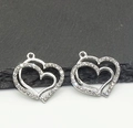 Detailed view of two silver hollow heart pendants with sparkling inset rhinestones - One Small Heart / Silver