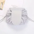 Flat lay of open silver drawstring makeup bag on white fabric with decorative card - Light Gray
