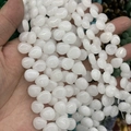 Close-up of hand holding a string of polished white water-drop crystal agate beads - 10mmx12mm / Natural White Jade