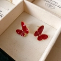 Élégantes boucles d'oreilles papillon rouges avec bord doré dans un écrin beige - Boucles d'Oreilles Clous Papillon Émail Rouge