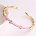 Close-up of gold-plated bamboo evil eye bracelet with pink enamel on white porcelain - Pink
