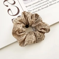 Chic leopard print scrunchie in brown fabric styled on a minimalist magazine background - Classic Leopard
