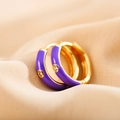 Close-up of golden hoop earring with purple enamel and a centered white zircon stone - Purple