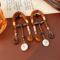 Primer plano detallado de pendientes bohemios de cuero y madera sobre libro - Café-Negro