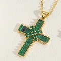 Dettaglio macro del ciondolo a croce dorata con zirconi verde smeraldo e catena fine - Zirconia Smeraldo Quadrata