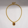 Detail einer goldenen Schlangenkette mit rotem Wassertropfen-Anhänger und weißen Zirkonsteinen - Wassertropfen Anhänger Halskette / Dunkelrot (Goldkette)