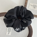 Détail d'un chouchou en tissu noir avec broderie de nœud blanc délicat - Broderie Nœud / Noir