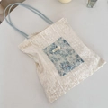 Gros plan du sac cabas en toile crème avec poche fleurie en dentelle bleue et détails - Dentelle Bleue + Velours Blanc