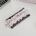 Détail d'une trousse à fleurs matelassée avec bordure en dentelle et pendentif floral - Noir avec motif floral rose