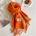 Close-up of orange gradient cashmere scarf with soft fringe and minimalist brand label - Orange