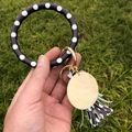 Porte-clés bracelet en cuir PU à pois avec pendentif en bois et pompon sur l'herbe - Noir à pois blancs