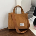 Bolso tote de pana marrón con correa ajustable y bolsillo delantero en mesa de madera - Marrón