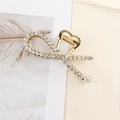 Close-up of elegant gold alloy hair claw clip with sparkling rhinestones in a ribbon design - Bow Rhinestone Gold