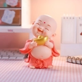 Cute monk figurine in orange robe holding golden ingot on warm pink desktop - Holding Ingot Pose (Large Red)