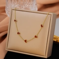 Elegant gold necklace with five red heart pendants draped over a luxury jewelry gift box - Five Enamel Hearts / Gold