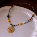 Détail de perles colorées et pendentif pièce dorée texturée dans un plat en céramique - Style Pendentif Pièce Lune Étoile Céleste / Or-Multicolore