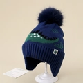 Close-up of kids winter knit hat with green dinosaur pattern and faux fur pom-pom - 3-8 Years / Blue