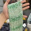Natural 2-3mm faceted green and white gradient semiprecious stone beads held in hand - Gradient Australian Jade 3mm