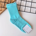 Close-up of sky blue ribbed cotton socks with minimalist brand tag on grid background - One Size / Blue