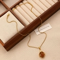 Detail of gold leaf necklace with amber gemstone pendant on a wooden jewelry display tray - Gold Oval Amber Necklace Style (11974)