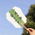 Calligraphy folding fan with 'Stay Calm' text against a sunny blue sky background - Ocean in Heart