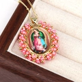 Macro shot of colorful religious oval pendant with pink beads on beige jewelry box lining - Pink