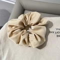 Gros plan d'un chouchou en velours beige orné de strass brillants sur fond de tissu doux - Beige