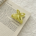 Close-up of a yellow acetate butterfly hair claw clip on an open book page - Mustard Green