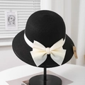 Detail of elegant Hepburn style straw hat with a large satin bow and UV protection tag - Adjustable (57.5cm) / Black