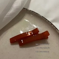 Dettaglio di fermagli ambra traslucidi su seta bianca e un piatto in ceramica bianca - Arancione